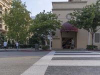 a building that is on the side of a street with people walking in it and some trees