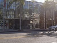 a silver car in front of a black and gold building on the side of a city street