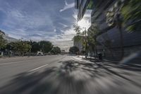 cars going by a city street with a blurry view of the sky and buildings