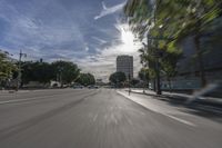 cars going by a city street with a blurry view of the sky and buildings