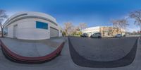 a fisheye lens photo of the street side with cars and buildings in the background