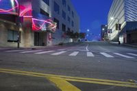 an empty city street at night with several neon lights lit up in pink and blue