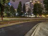 a city street with tall buildings and green grass in the background at night or evening