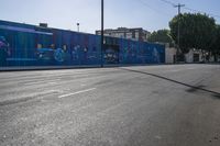 a view of a city street with an outdoor mural that looks like people performing on it