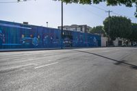 a view of a city street with an outdoor mural that looks like people performing on it