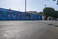 a view of a city street with an outdoor mural that looks like people performing on it