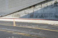 the city street is lined with buildings and empty spaces in the background, with a concrete wall on the far side of the road