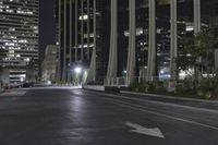 a very wide empty street at night near the tall building area of a city block