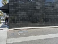 a black brick wall with a yellow fire hydrant on it's side of a road