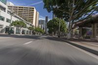 a city street with buildings and cars driving by it, with the words stop right by and a blurry image of trees behind the car