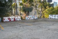 a parking lot full of different colored graffiti in the middle of it with buildings in the background