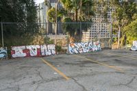 a parking lot full of different colored graffiti in the middle of it with buildings in the background