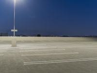 empty parking lot near a light pole at night at dusk area with lights glowing and cityscape in background