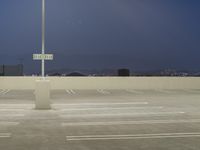 empty parking lot near a light pole at night at dusk area with lights glowing and cityscape in background