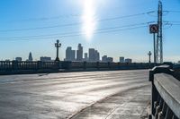 an empty parking lot with many electrical lines above it and buildings in the distance, with blue sky