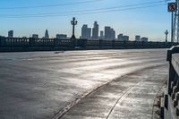 an empty parking lot with many electrical lines above it and buildings in the distance, with blue sky