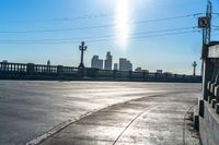 an empty parking lot with many electrical lines above it and buildings in the distance, with blue sky