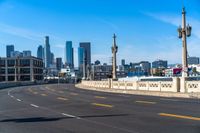 a motorcycle rides down a highway through a city with tall buildings in the distance on a clear day