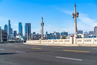 a motorcycle rides down a highway through a city with tall buildings in the distance on a clear day