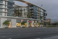 a stop sign is shown in front of a store front at dusk and it has palm trees outside