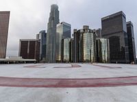 a city has some big high rise buildings in the background while an empty parking lot lies beneath