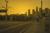 an empty highway with power lines leading to city buildings in the back ground and road tracks