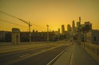 an empty highway with power lines leading to city buildings in the back ground and road tracks