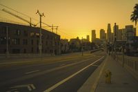 an empty highway with power lines leading to city buildings in the back ground and road tracks