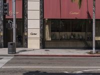 a street with a corner and palm trees in the background, some with red awnings and a stop light