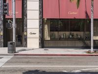 a street with a corner and palm trees in the background, some with red awnings and a stop light