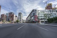 cars and buses travel down an empty city street near tall buildings in downtown, calgary