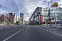 cars and buses travel down an empty city street near tall buildings in downtown, calgary