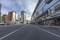 cars and buses travel down an empty city street near tall buildings in downtown, calgary