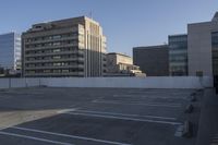 a parking lot has two parking meter and two red telephone booths in it, the city behind it