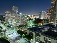 nighttime view of a city area with tall buildings and a street light up at the center