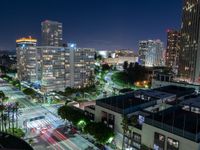 nighttime view of a city area with tall buildings and a street light up at the center