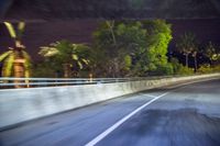 a car on the side of the road with trees in the background at night and a street light at the end