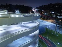 a curved walkway going over an elevated bridge in the evening with cars going down it