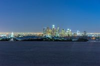 a city skyline at night with the lights off in the background a field and a building