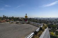 a man sits on the curb near a stop sign on a hill top overlooking a city