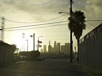 an empty highway with power lines leading to city buildings in the back ground and road tracks