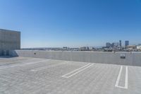 a large parking lot on top of a building in front of tall buildings with a clear blue sky