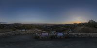 the sun sets behind a city with hills in the background and signs to use as a seating area for people to sit