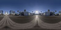 a street view of buildings and palm trees at sunset or sunrise, from a fish - eye lens