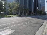 a person walking down a deserted city street with skyscrapers in the background in the daytime