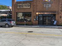 a building with a sign for fresh fish in it in front of cars and on the street