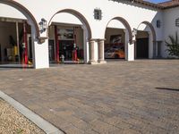 an driveway outside a building with red fire hydrant in the foreground and two pillars