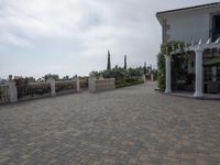 a large brick patio is adjacent to a private residence with a garden and fountain area