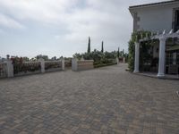 a large brick patio is adjacent to a private residence with a garden and fountain area