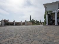 a large brick patio is adjacent to a private residence with a garden and fountain area